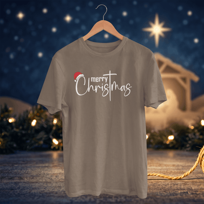 A taupe gray short-sleeve t-shirt on a wooden hanger, featuring a 'merry Christmas' graphic with a Santa hat accent, set against a festive, blurred Christmas night background.