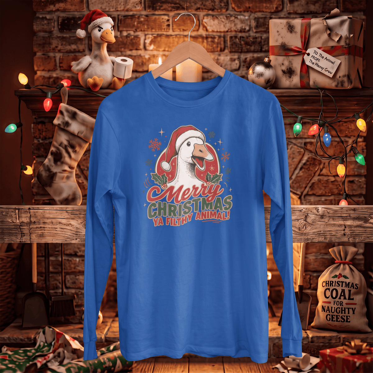A royal blue long-sleeve t-shirt with a Christmas goose graphic hanging on a wooden hanger. The graphic features a white goose wearing a red Santa hat with the text 'Merry Christmas Ya Ducky Animal!'.