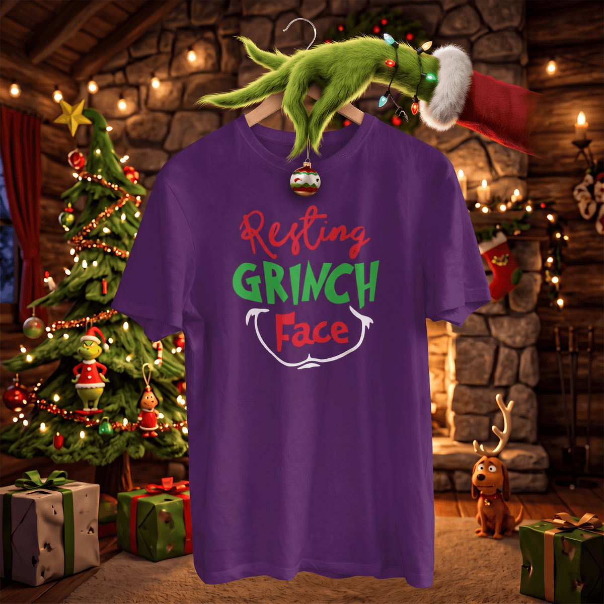 A purple short-sleeve t-shirt with a 'Resting GRINCH Face' graphic, hanging on a hanger decorated with a Christmas ornament and a green Grinch hand wearing a Santa hat. The scene is set in a cozy, warmly lit Christmas village with a decorated tree, gifts, and a stone fireplace.